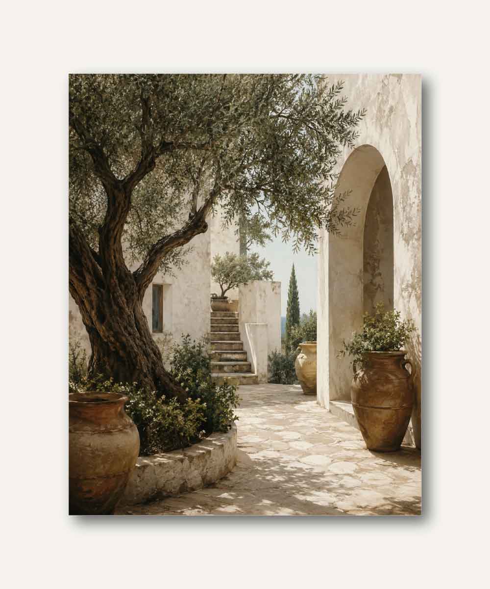 Patio mediterráneo con olivo centenario, muros encalados, sendero de piedra y cerámicas artesanales iluminadas por la luz del sol.